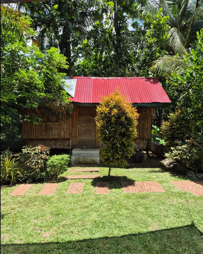 Bamboo kubo with red roof among trees