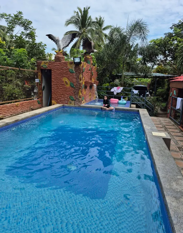 Blue swimming pool with eagle statues and palm trees
