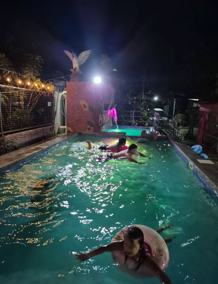 Guests enjoying a night swim in the lit pool